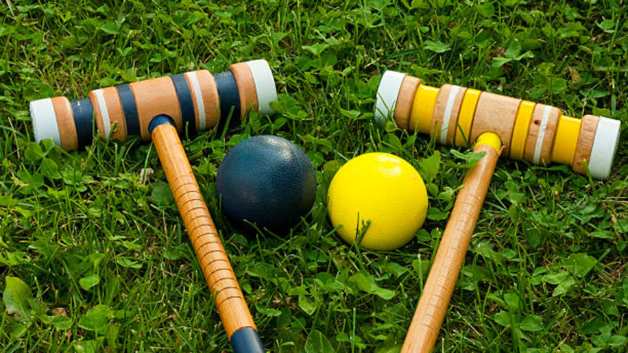 two croquet mallets and balls on a grassy background